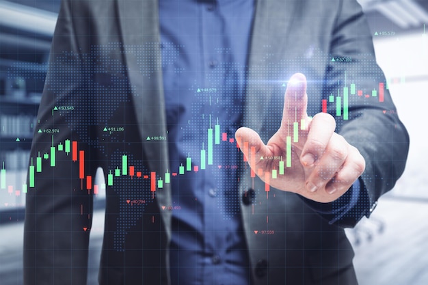 Geschäftsperson Hand zeigt auf kreative leuchtende Forex-Chart-Schnittstelle in verschwommenem Bürointerieur Handels- und Investitionskonzept Doppelbelichtung