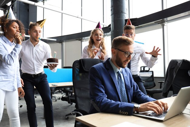 Geschäftsteam feiert Geburtstag eines Kollegen im modernen Büro.