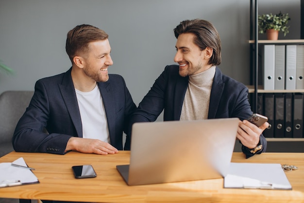 Geschäftsteamarbeit zwei lächelnde Unternehmensgeschäftsmänner, die zusammen auf Laptop arbeiten