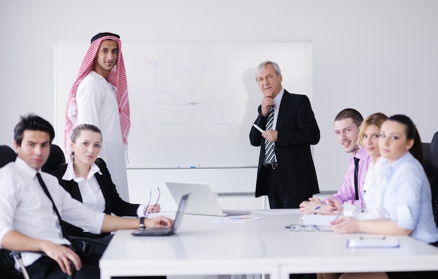 Geschäftstreffen - Gutaussehender junger arabischer Mann, der Kollegen seine Ideen vorstellt und nach Ideen für erfolgreiche Investitionen in einem hellen, modernen Büroraum lauscht