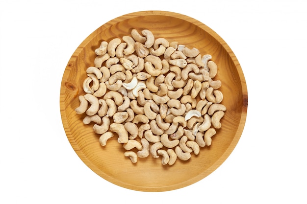 Geschälte Cashewnüsse in einer hölzernen Kiefernplatte auf einem weißen lokalisierten. Schalenreihe mit Cashewnüssen, Draufsicht.