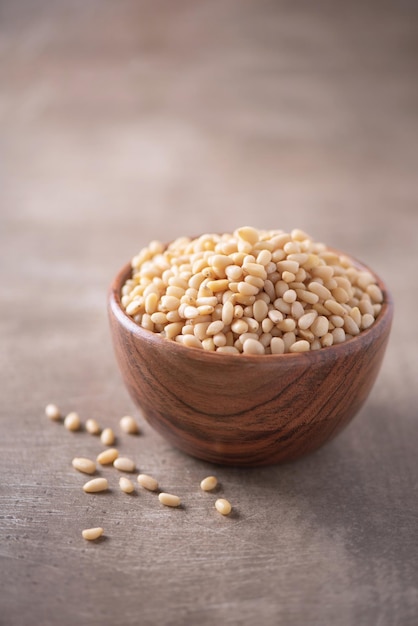 Geschälte rohe Pinienkerne in Holzschale auf Holz strukturierten Hintergrund Platz kopieren Superfood vegane vegetarische Kost Konzept Makro von Zeder Pinienkernen Textur selektiver Fokus Gesunder Snack