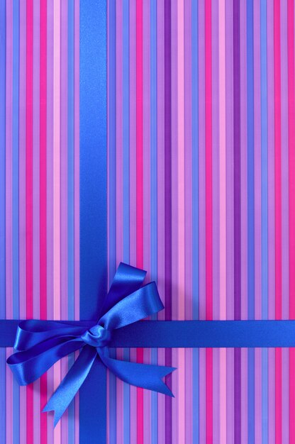 Geschenk aus violettem streifenpapier mit blauem satinband.