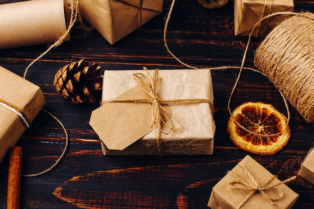 Geschenk des Kraftpapiers vor dem hintergrund der getrockneten Orange, Zimt, Kiefernkegel, Anis auf einem Holztisch