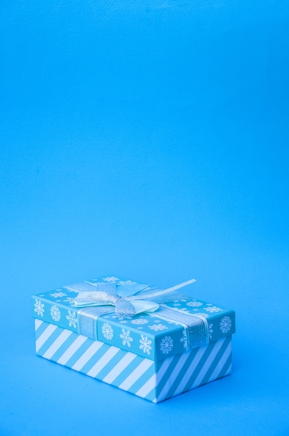 Geschenk Eine blaue Geschenkbox mit Schleife ist auf blauem Hintergrund isoliert Eine Neujahrskarte Weihnachten