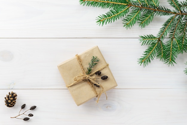 Geschenk für Weihnachten und Neujahr mit einem Tannenzweig und Zapfen auf einem Holztisch. Rustikaler Stil.