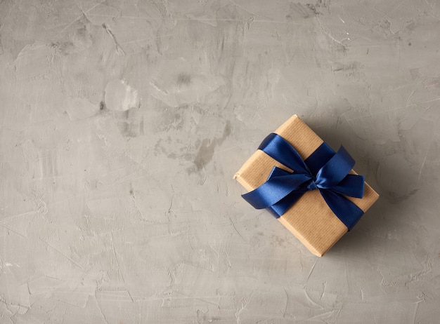 Geschenk in braunes Kraftpapier eingewickelt und mit einer blauen Seidenschleife gebunden