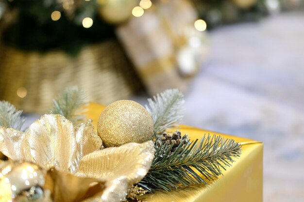 Geschenk in einer Goldbox in der Nähe des Weihnachtsbaums. Bokeh. Hintergrund. Ruhige Farben, Nahaufnahme.