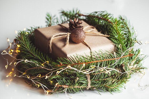 Geschenk in Kraftpapier in einem Kranz von Weihnachtsbäumen. Weihnachtsstimmung, Neujahr, Auf weißem Hintergrund