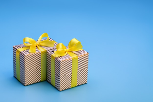 Geschenk in zwei Schachteln, in Weihnachtspapier eingewickelt und mit gelbem Band mit Schleife gebunden. Überraschung für jeden Feiertag und jedes Ereignis, auf hölzernem Hintergrund.