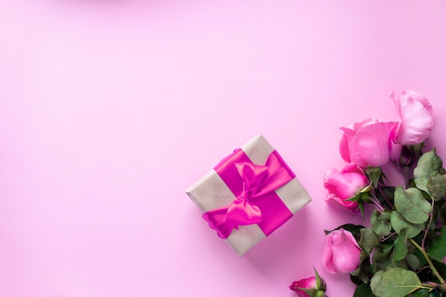 Geschenk mit rosa Band und rosa Rosenstrauß gebunden. Valentinstag, Weihnachten, Muttertag, Geburtstagsgeschenke. Grußkartenkonzept