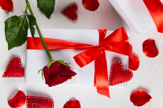 Geschenk mit rotem Band, roter Rose und Herz auf Weiß