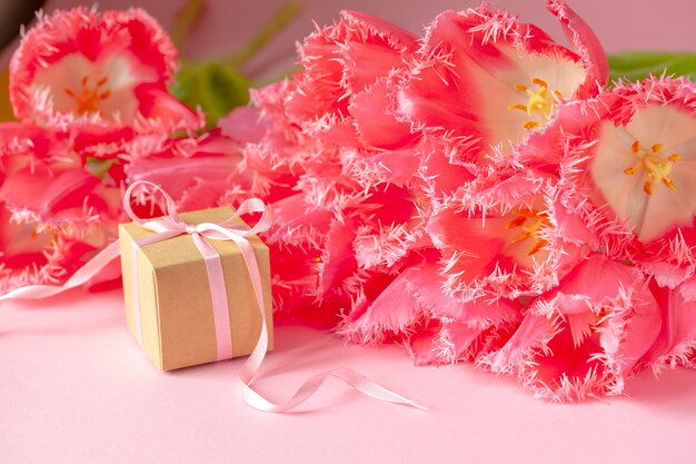 Geschenk- oder Geschenkbox mit schönem Strauß rosa Tulpenblumen auf rosa Oberfläche