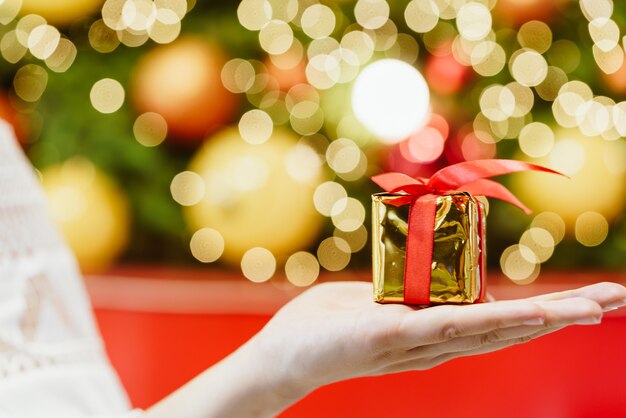 Geschenk zur Hand mit Weihnachts-Bokeh-Lichtern