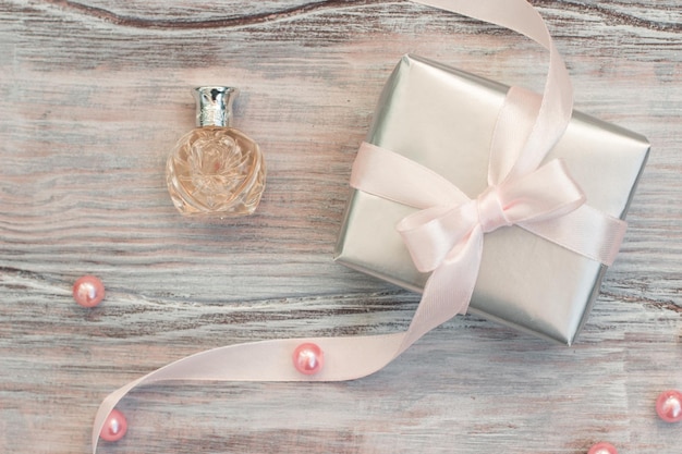 Geschenkbox aus Silberpapier mit rosa Schleife und Parfüm