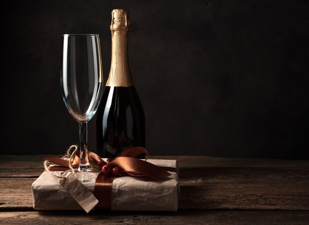 Geschenkbox, Champagner und Weinglas auf einem Holztisch