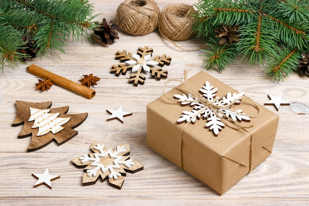 Geschenkbox im Kraftpapier mit Weihnachtsdekoration, Schnurseil, Konzept, Draufsicht über hölzerne Tischplatte, Weihnachtsverzierungen und Geschenkgrenze mit Schneeflocken und Sternen