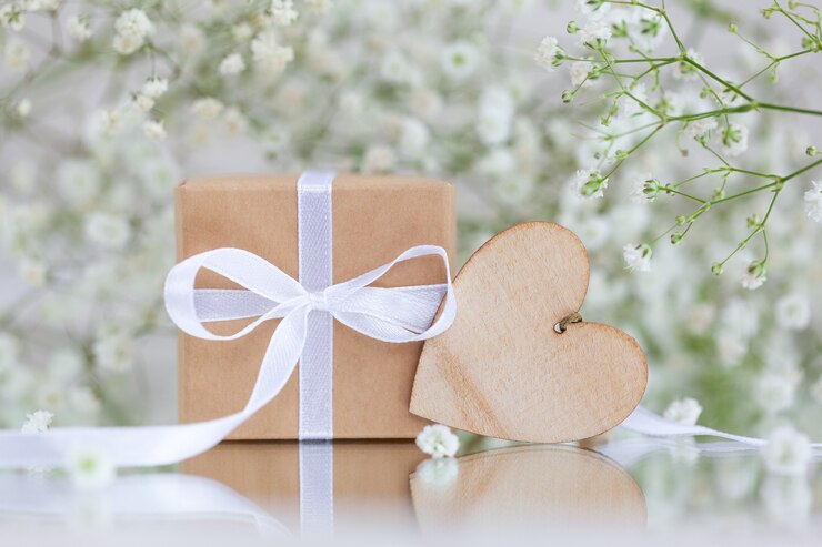 Foto geschenkbox in braunem papier mit holzherz und weißen blüten von gypsophila paniculata. grußkarte.