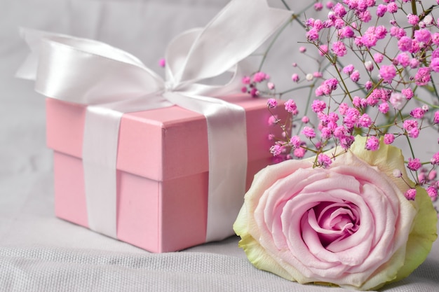 Geschenkbox mit Blumen auf rosa Valentinstaghintergrund.