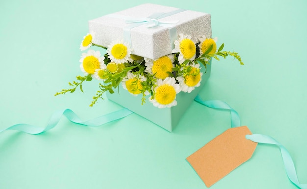 Geschenkbox mit Blumen im Inneren, verziert mit einem Band