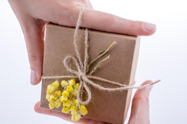 Geschenkbox mit Blumen in der Hand