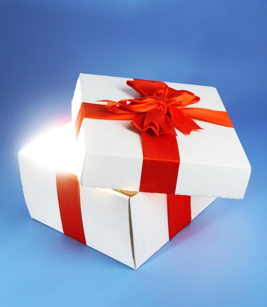 Geschenkbox mit hellem Licht auf blauem Hintergrund