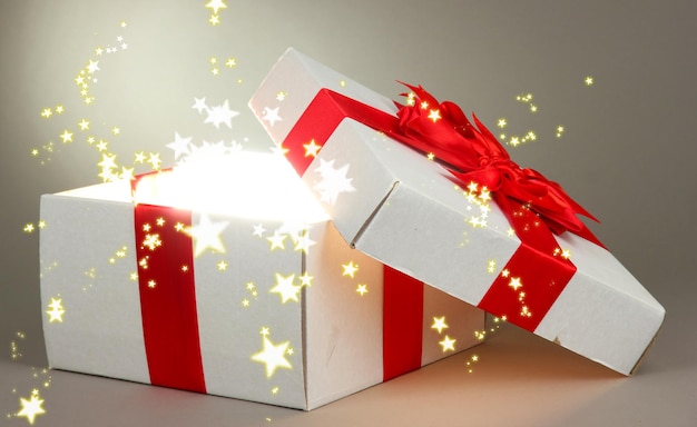 Geschenkbox mit hellem Licht auf grauem Hintergrund