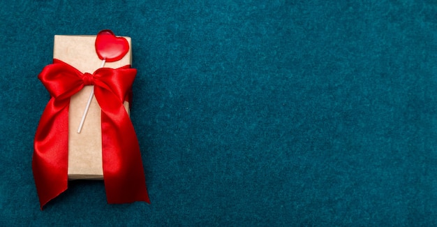 Geschenkbox mit Klebeband und Herz auf einem hellen blauen Hintergrund.