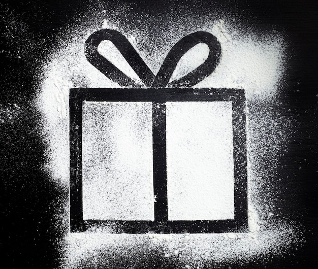 Geschenkbox mit Mehl auf einem schwarzen Tisch gezeichnet