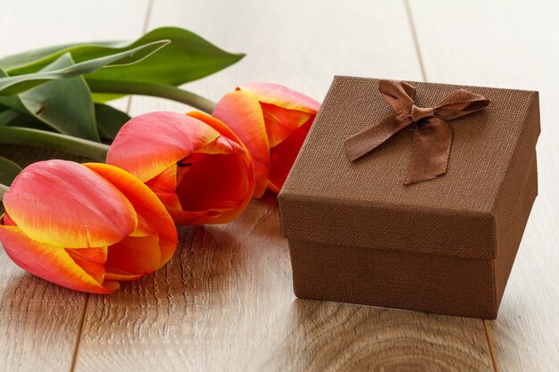 Geschenkbox mit roten Tulpen auf den Holzbrettern. Grußkartenkonzept.