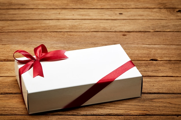 Foto geschenkbox mit roter schleife auf holz