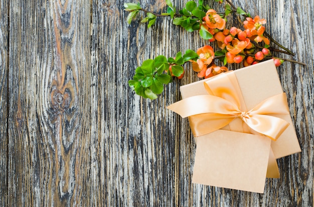 Geschenkbox mit Schleifenband, leerem Etikett und zartem blühendem Zweig.