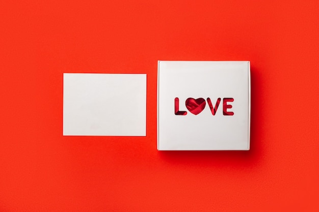 Geschenkbox mit Text Liebe und Karte auf einem roten Hintergrund. Zusammensetzung Valentinstag. Banner. Flache Lage, Draufsicht.