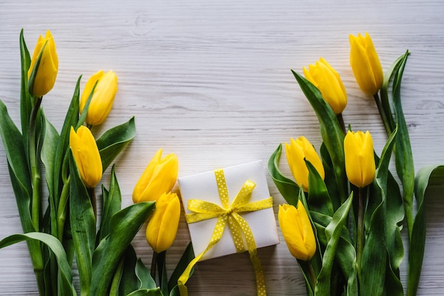 Geschenkbox mit Tulpen auf weißem Holzhintergrund Platz für Nachricht Blumenkonzept Feiertagsgrußkarte zum Valentinstag Frauen Muttertag Ostern Geburtstag Draufsicht flach gelegt