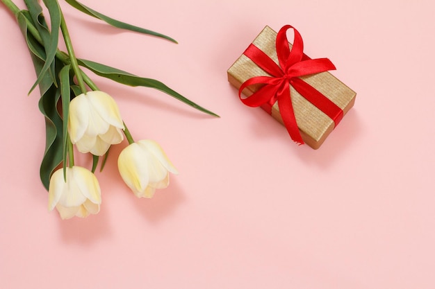 Geschenkbox mit Tulpenblumen auf einem rosa Hintergrund