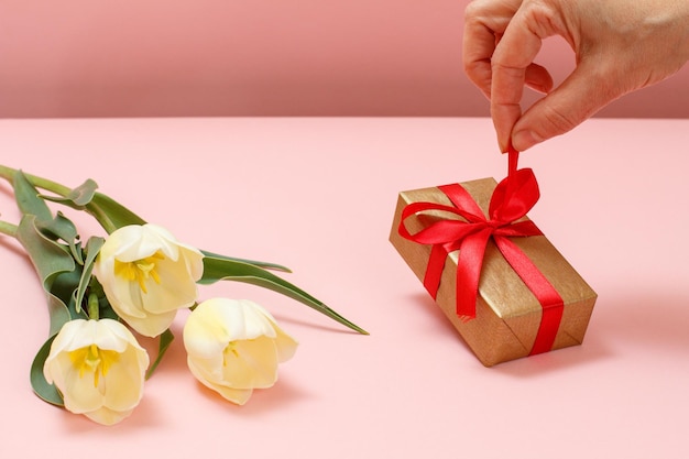 Geschenkbox mit Tulpenblumen auf einem rosa Hintergrund