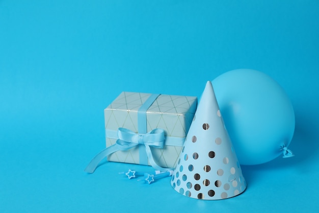 Geschenkbox, Partyhut, Ballon und Kerzen auf blauem Hintergrund