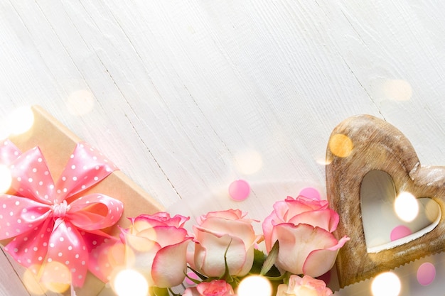 Geschenkbox rosa Rosen Holzherz auf Holz weißer Hintergrund mit Bokeh-Lichtern Festliche Karte Kopierraum