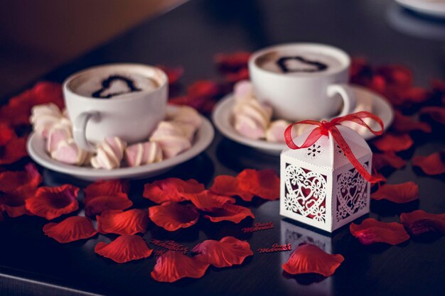 Geschenkbox und Kaffeetasse mit Dampf und Rosenblättern