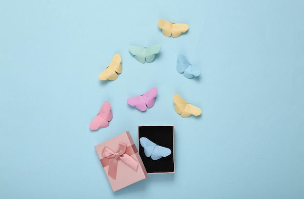 Geschenkbox und Origami-Schmetterlinge auf blauem Hintergrund
