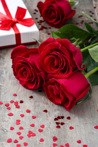 Geschenkbox und rote Rosen auf hölzernem Valentinsgrußkonzept