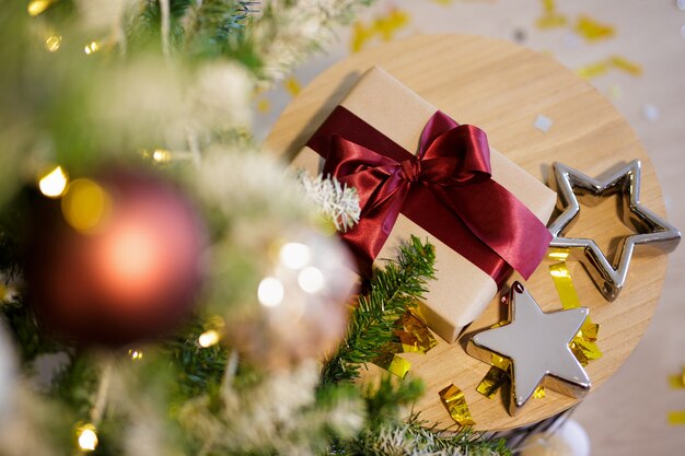 Geschenkbox und silberne Sterne in der Nähe des geschmückten Weihnachtsbaums