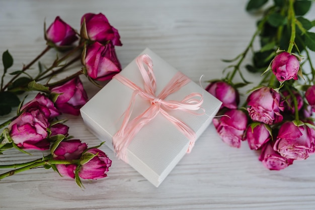 Geschenkbox und Strauß rosa Rosen auf Holzhintergrund Postkarte Platz für Textnachricht Blumenkonzept Feiertagsgrußkarte zum Valentinstag Frauen Muttertag Ostern Alles Gute zum Geburtstag