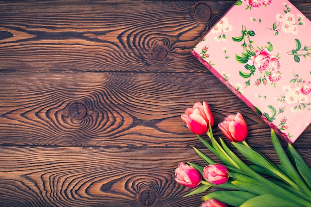 Geschenkbox und Tulpenblumen auf rustikalem Tisch für den 8. März Internationaler Frauentag Geburtstag oder Muttertag schöne Frühlingskarte