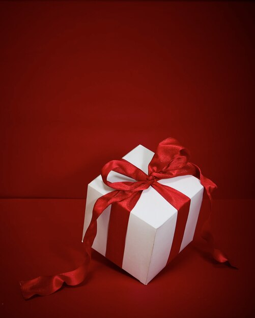 Geschenkbox Weihnachten mit rotem Band auf rotem Grund