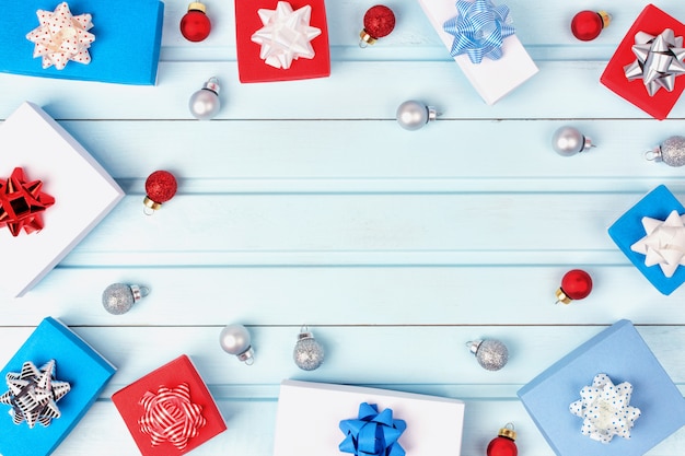 Geschenkboxen mit Bögen und Weihnachtskugeln werden in einem Kreis auf Blau ausgerichtet