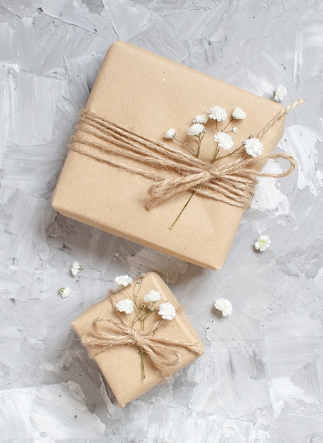 Geschenkboxen mit kleinen weißen Blumen auf grauem Hintergrund