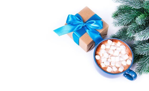 Geschenkboxen mit neben Tannenzweigen und Tasse Kakao mit Marshmallow