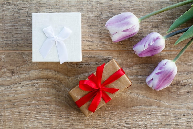 Geschenkboxen mit roten Bändern und schönen lila Tulpen Konzept, an Feiertagen ein Geschenk zu geben