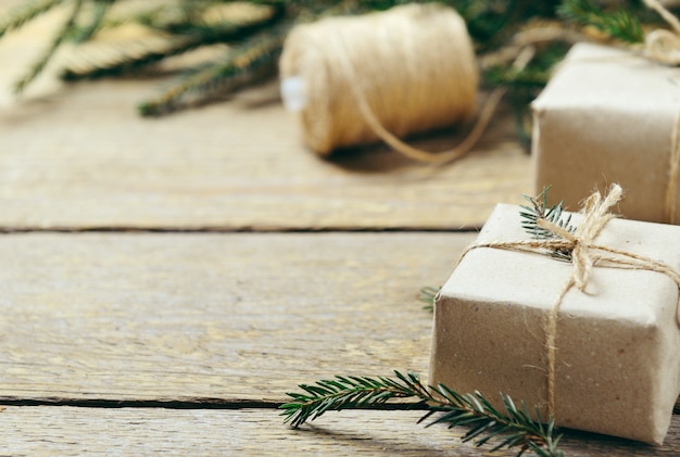 Foto geschenkboxen mit tannenzweigen auf einem hölzernen hintergrund.